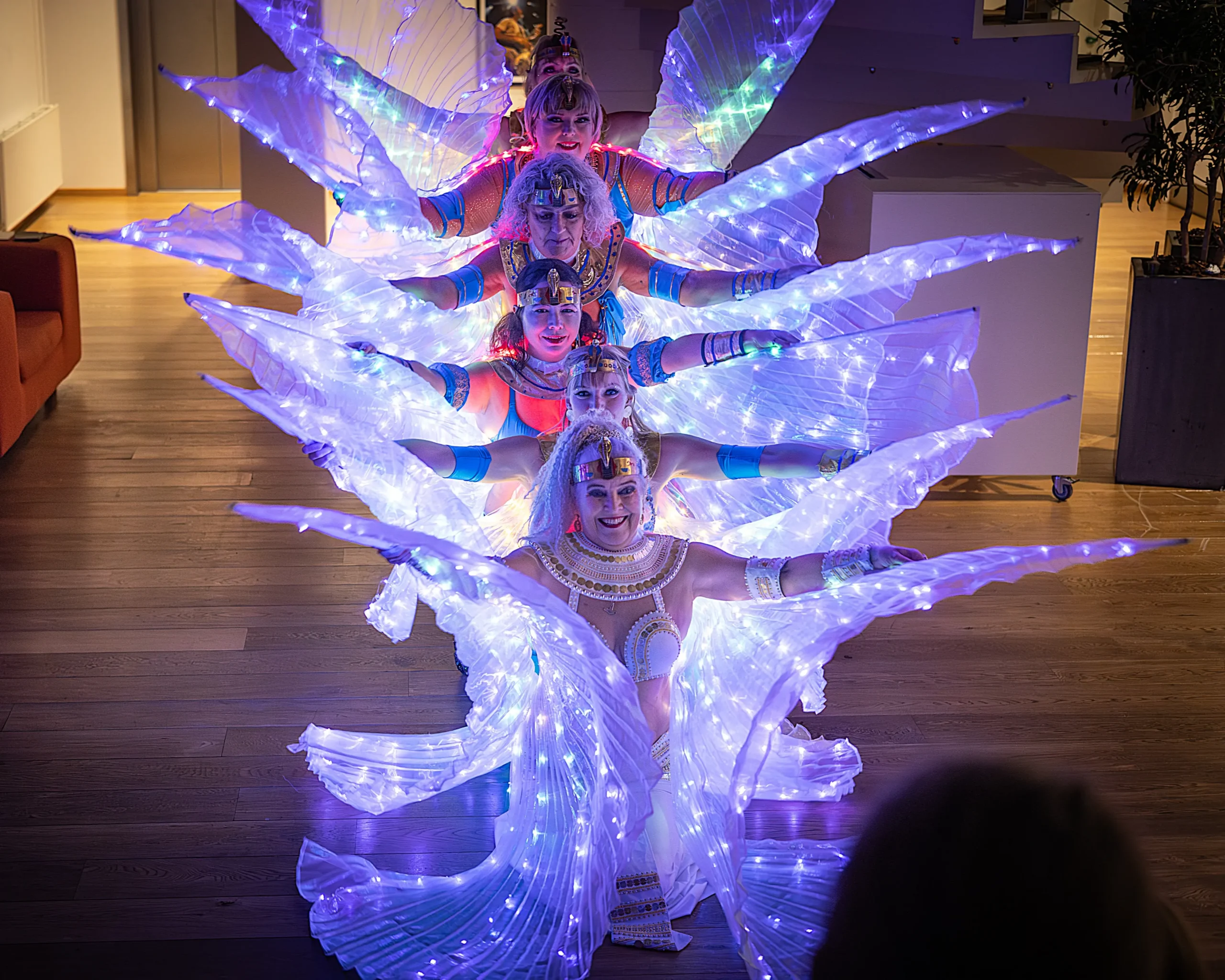 Ensemble Amira danser med lysende hvide Isis-vinger på Kolding Bibliotek ved Kolding Light Festival 2024. Aziza sidder forrest
