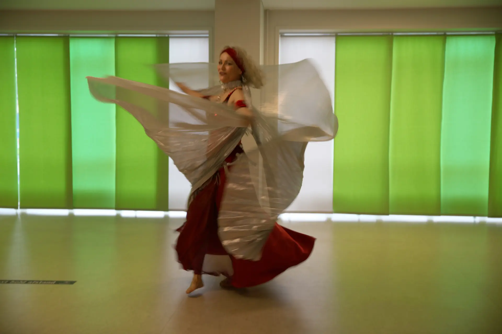 En tysk gæstedanser udfører en yndefuld dans med store, hvide Isis-wings ved Bellydance Dream Hafla 2025 i Fredericia.