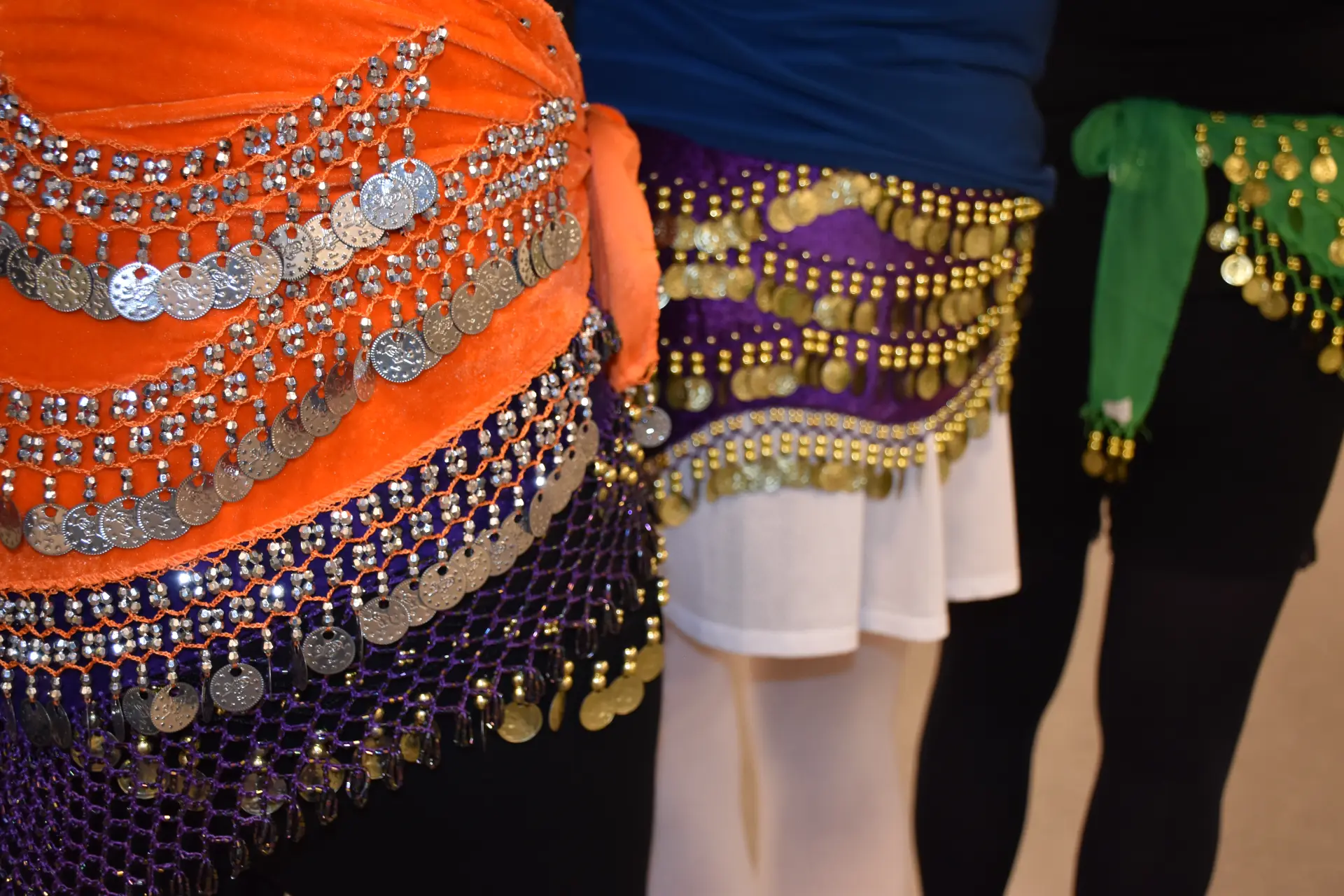 3 hofter med møntbælter på i forskellige farver