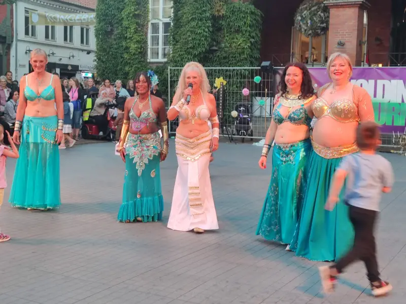 Aziza præsenterer medlemmerne af Ensemble Amira for publikum ved Kolding Kulturnat